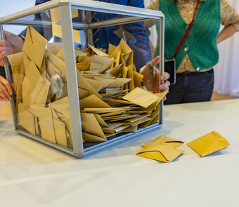 Le Président du bureau de vote a ouvert l'urne et verse les bulletins sur la table pour procéder au dépouillement.