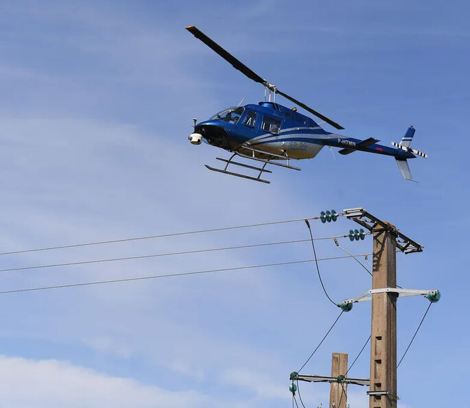 Hélicoptère survolant lignes électriques